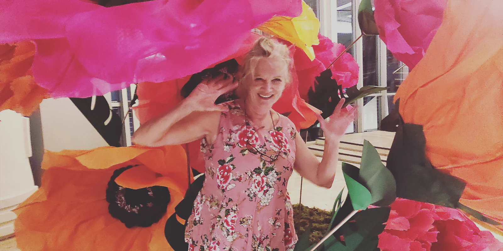 Giant tissue paper poppies in pink, orange and yellow towering over a visitor