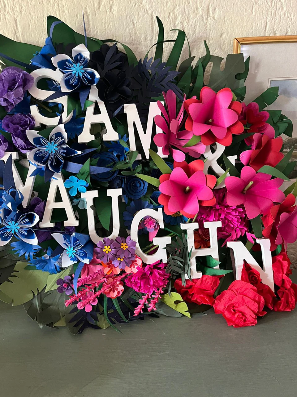 Cut paper letters spelling Sam and Vaughn set into pink, blue and red paper flowers