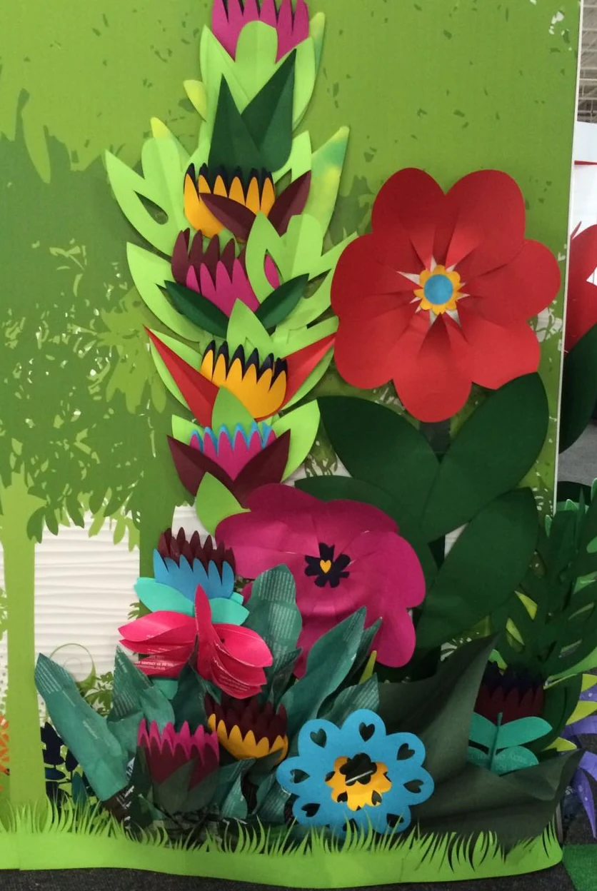 A green panel covered in cut paper flowers and leaves