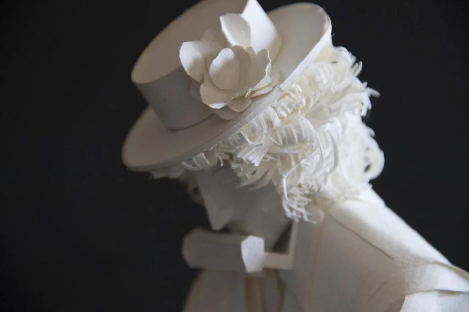 Bob Dylan in white paper: a wide-brimmed hat with a paper rose, and a fringed collar