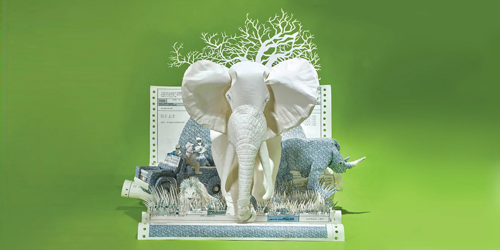 A white paper elephant and rhino rising out of printed pages, on a green backdrop